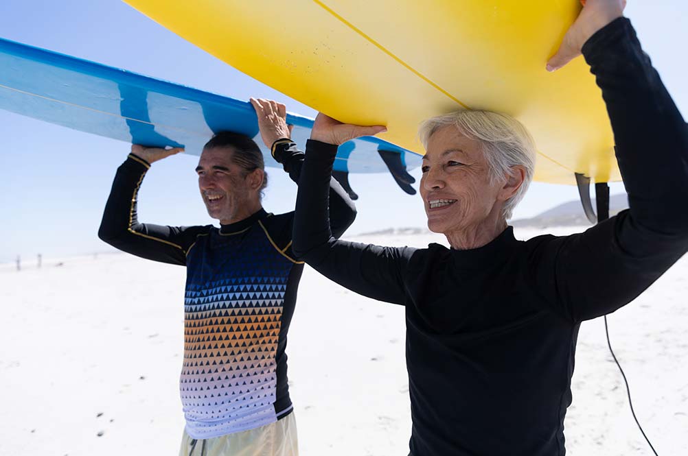 Senior couple holding surfboards on the beach
