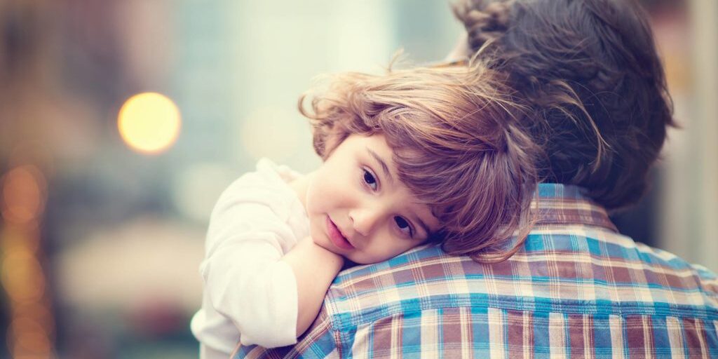 Little girl with her head resting on her Dad's shoulder.